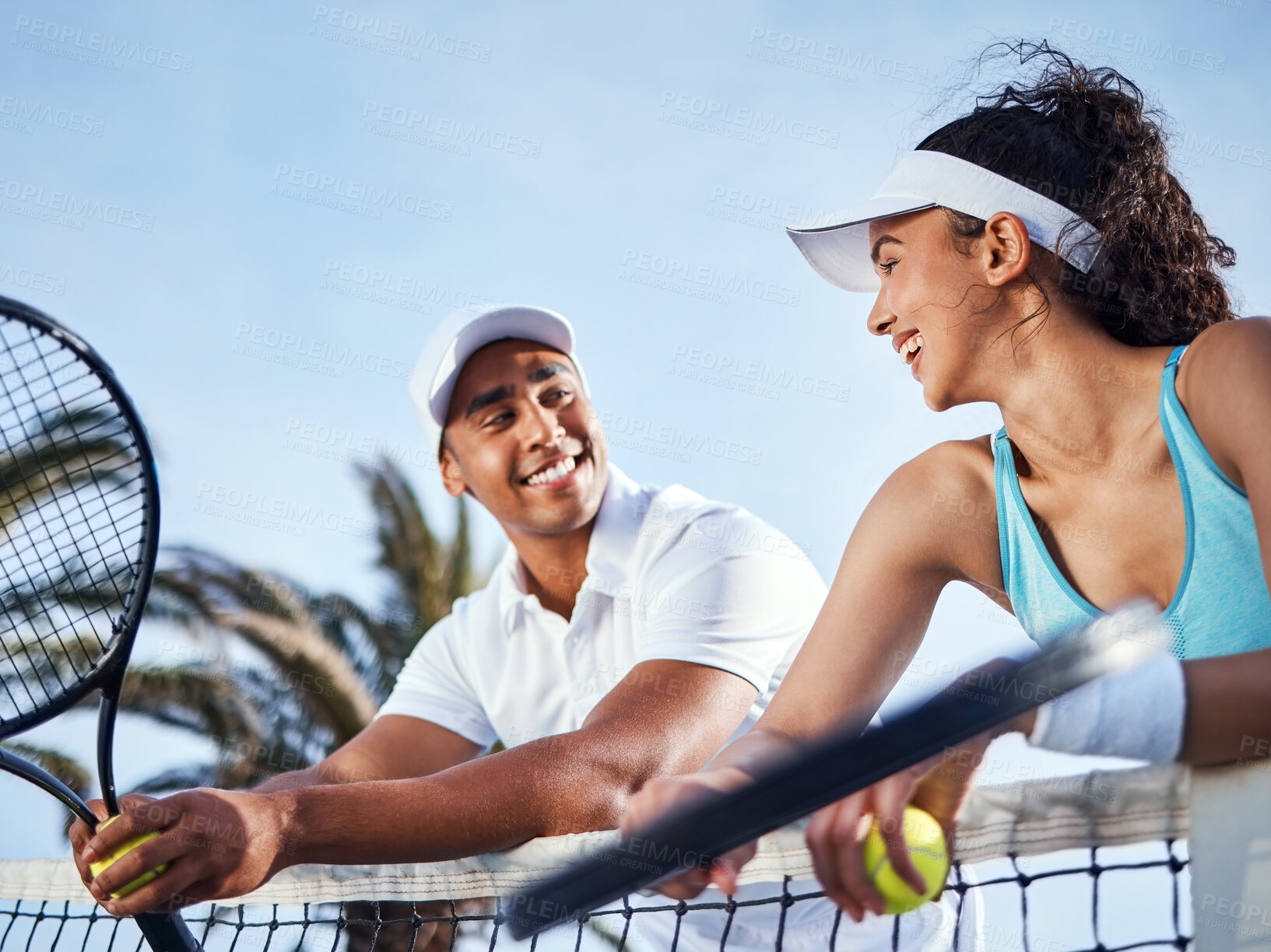 Buy stock photo Shot of two tennis players standing together and leaning on the net during practice