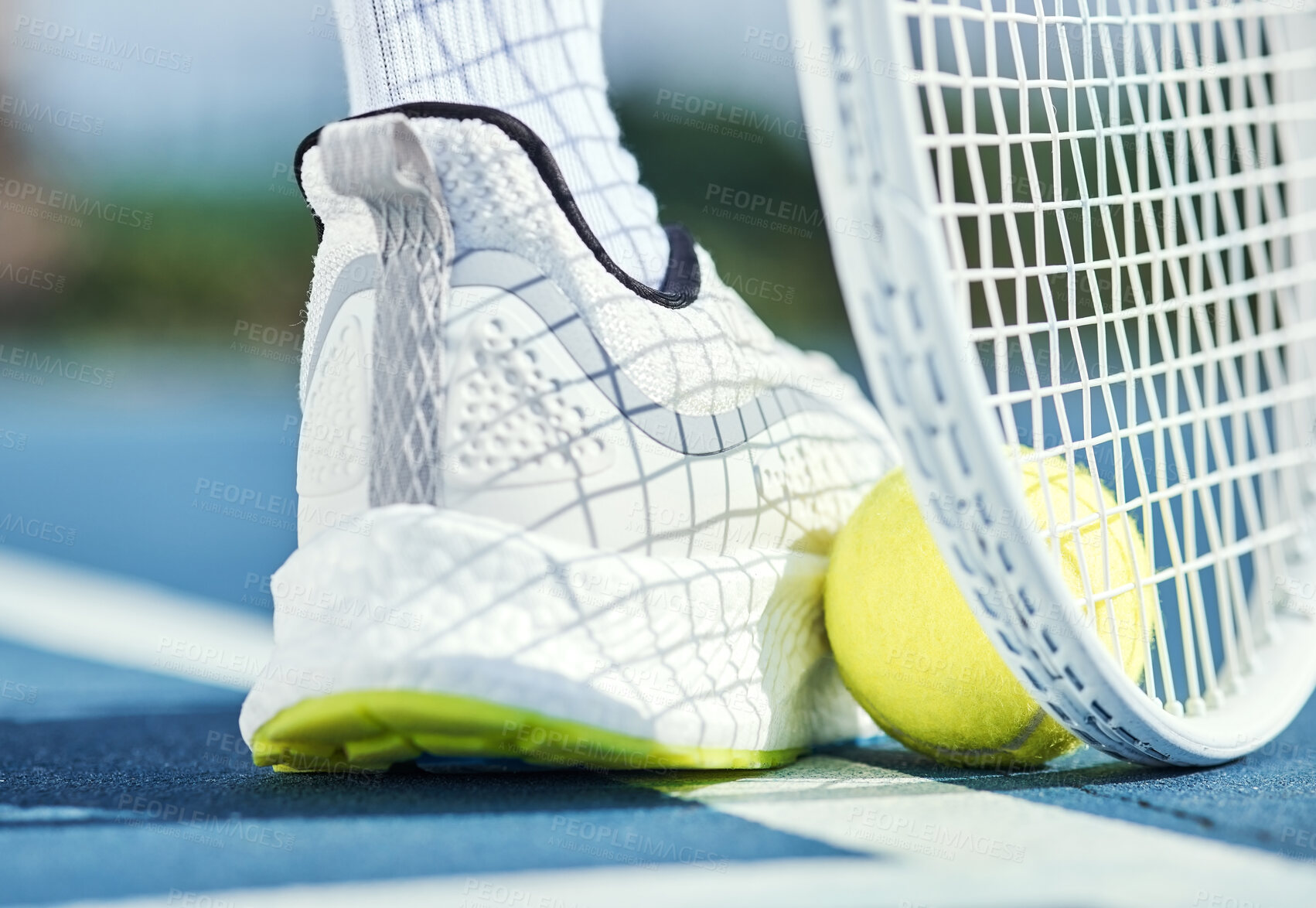 Buy stock photo Cropped shot of an unrecognisable man using his foot and racket to pick up a tennis ball during practice