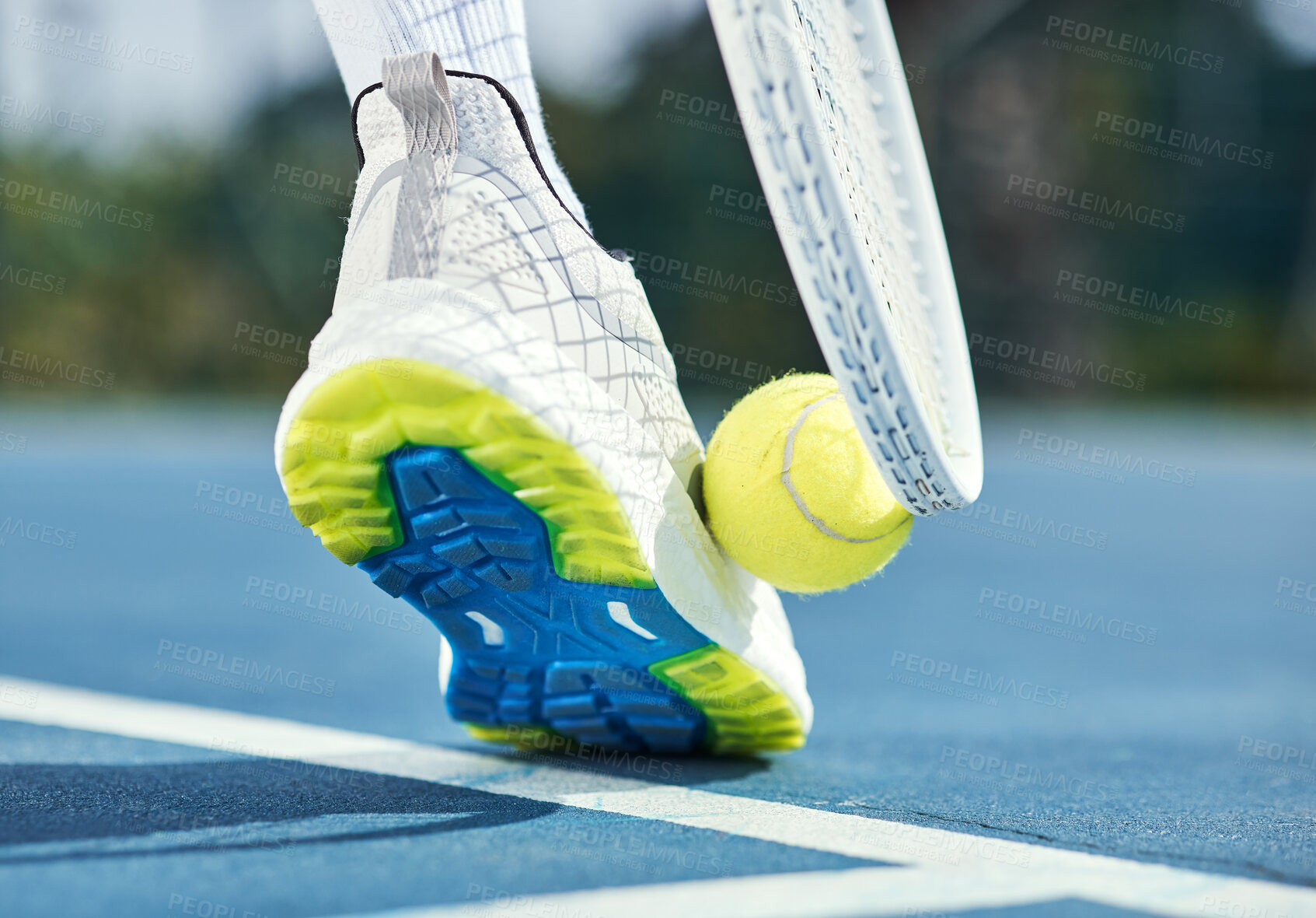 Buy stock photo Cropped shot of an unrecognisable man using his foot and racket to pick up a tennis ball during practice