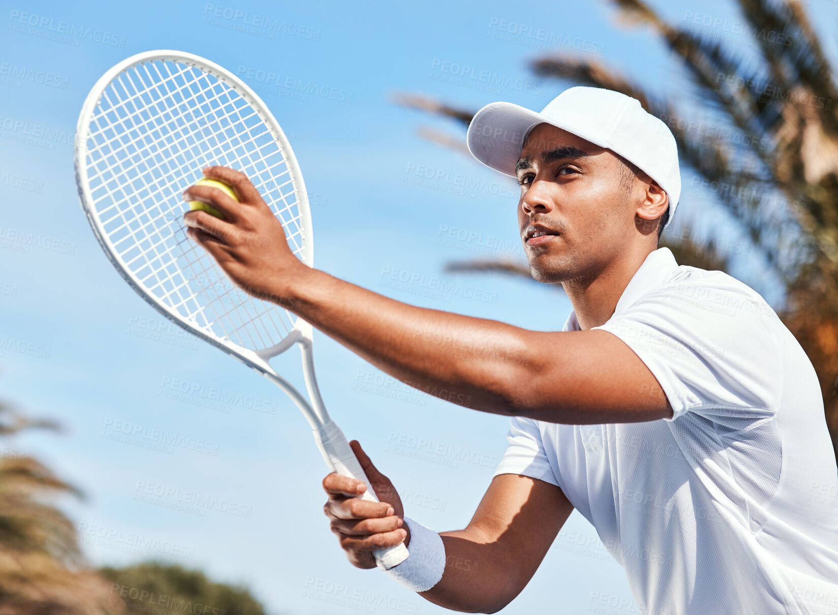 Buy stock photo Shot of a handsome young man standing alone and looking contemplative before serving the ball during a tennis match