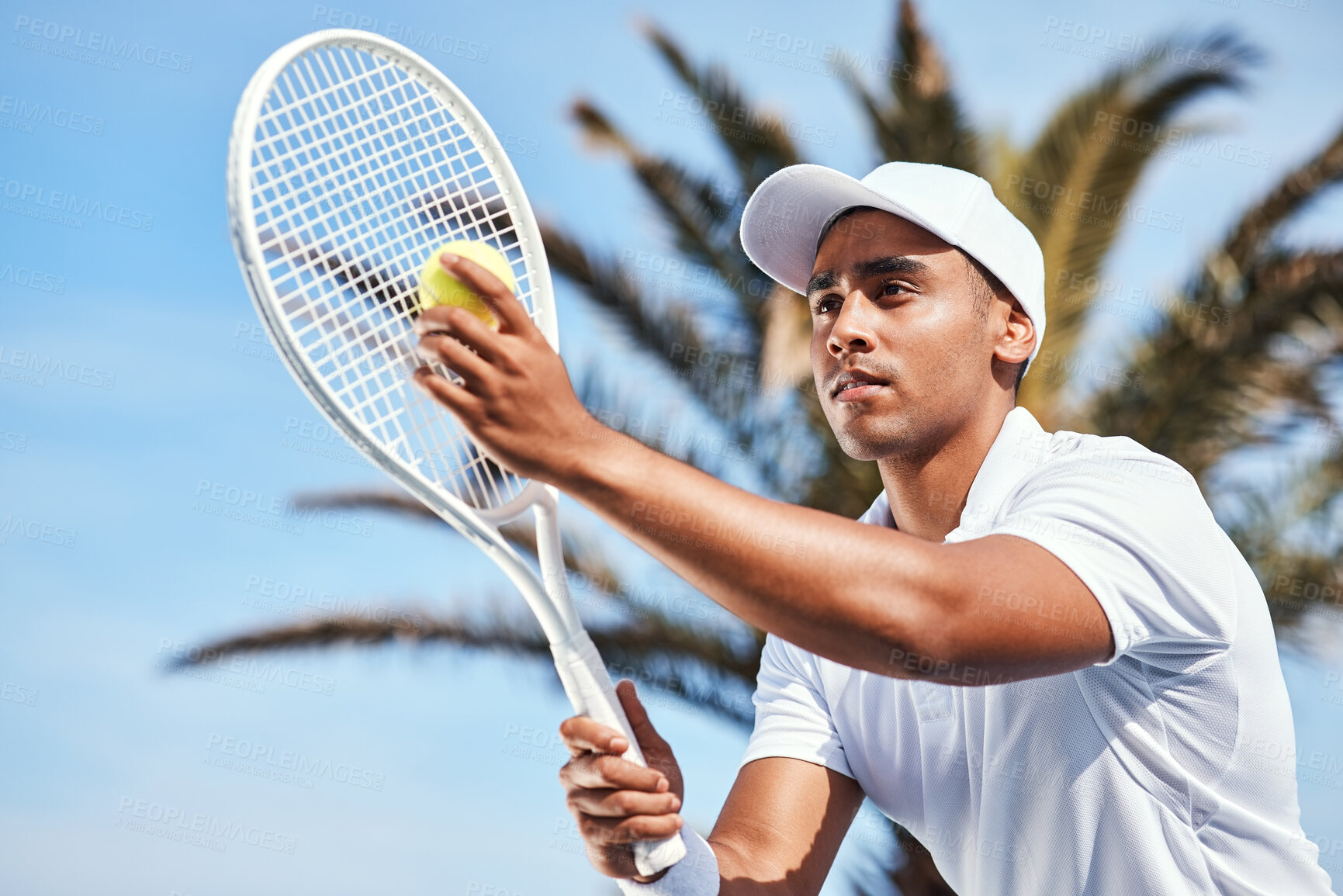 Buy stock photo Shot of a handsome young man standing alone and looking contemplative before serving the ball during a tennis match