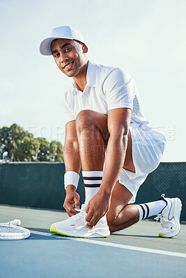 Buy stock photo Full length shot of a handsome young man kneeling down to tie his shoelaces before tennis practice