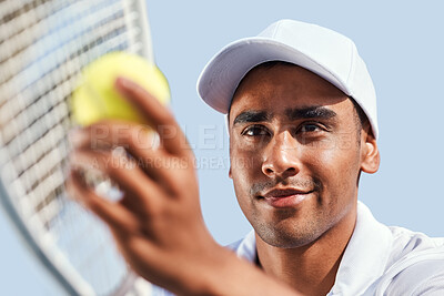 Buy stock photo Shot of a handsome young man standing alone and looking contemplative before serving the ball during a tennis match