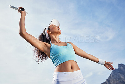 Buy stock photo Low angle shot of an attractive young woman standing alone and practicing her serve during tennis practice