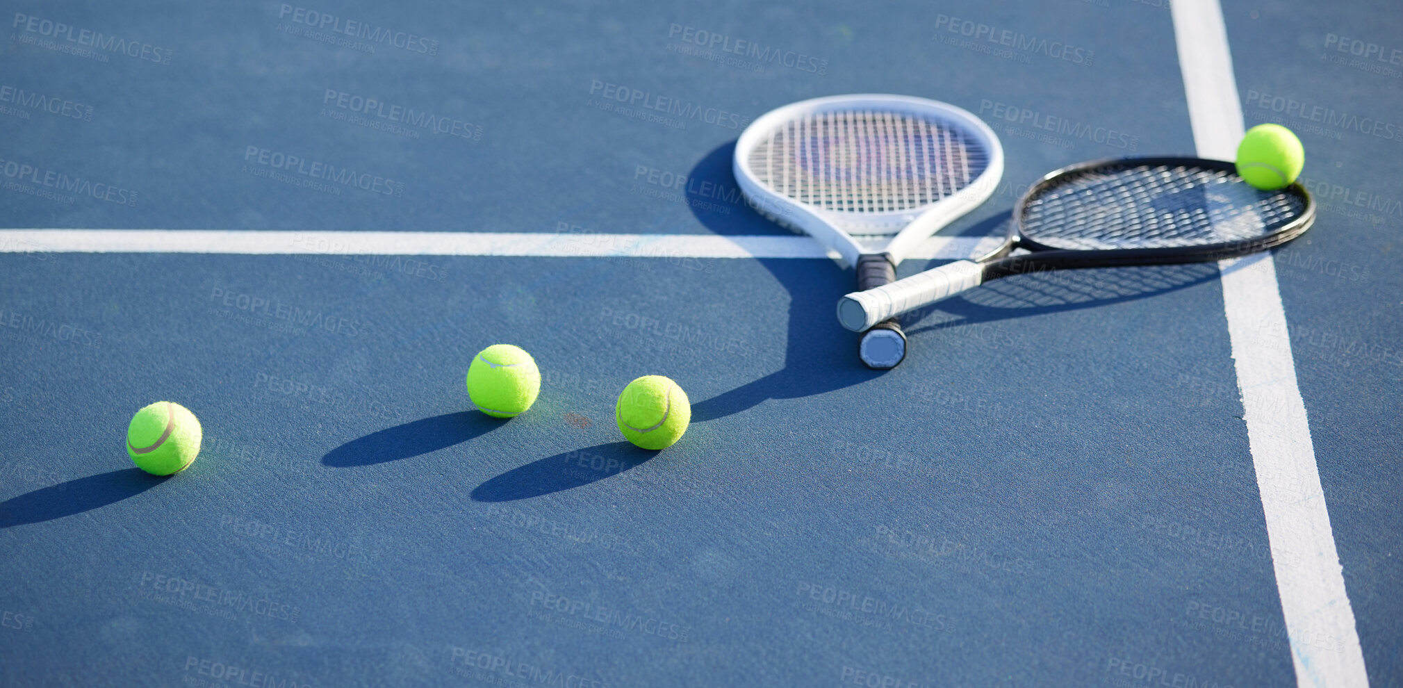 Buy stock photo Shot of two tennis rackets and tennis balls on a court during the day