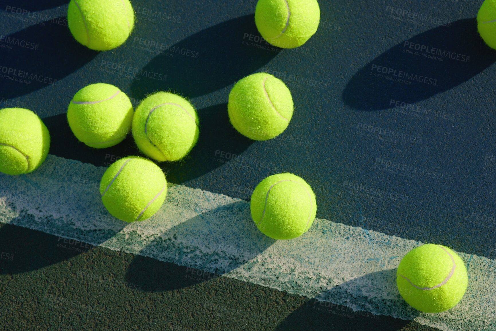 Buy stock photo Shot of an empty tennis court and tennis balls during the day