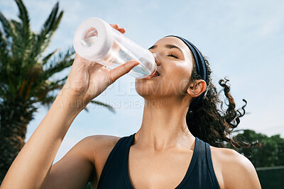 Buy stock photo Shot of a young woman drinking water during her tennis match