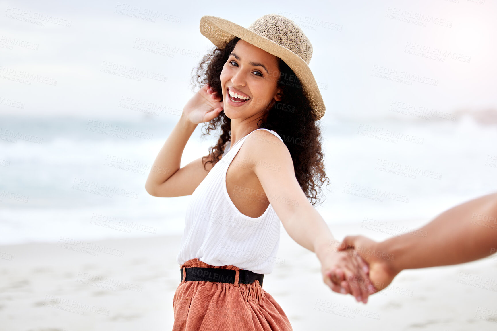 Buy stock photo Beach, portrait and couple holding hands for holiday, vacation and travel with smile in summer hat. Excited and young woman with love, support and walking by ocean or sea for romance and fashion