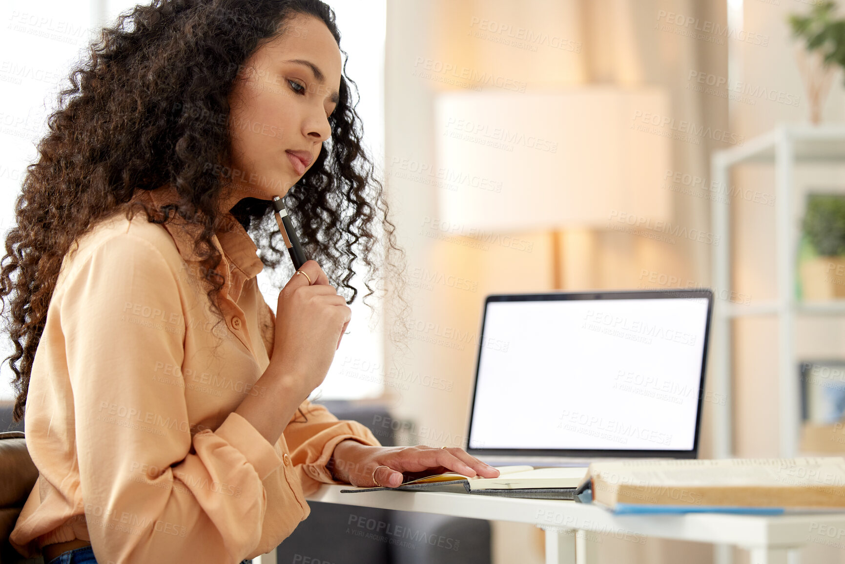 Buy stock photo Shot of a young woman making notes while working from home