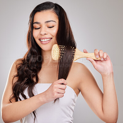 Buy stock photo Studio shot of a young woman brushing her hair