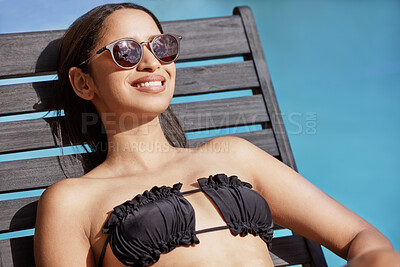 Buy stock photo High angle shot of an attractive young woman suntanning poolside