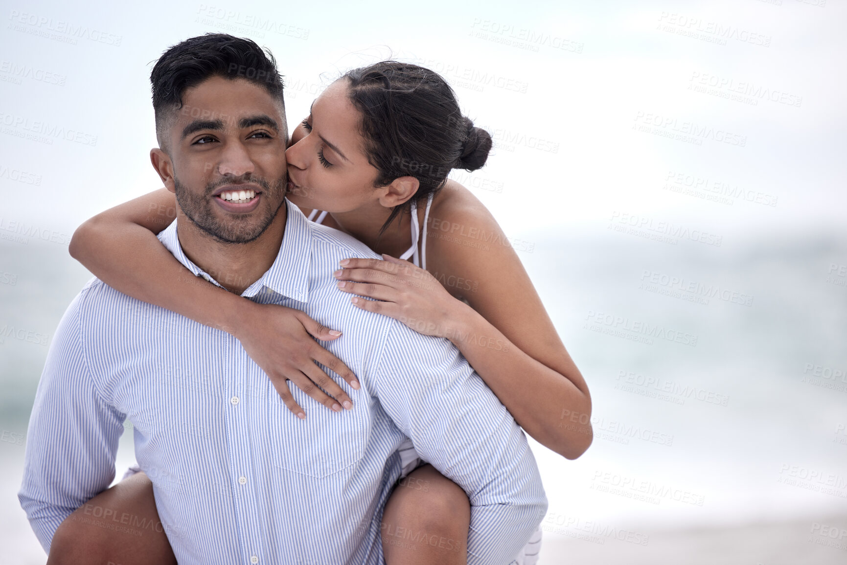 Buy stock photo Love, piggyback and couple at beach for travel, summer vacation or adventure. Smile, ocean and happy woman kiss man on afternoon date for honeymoon, anniversary or weekend trip in California