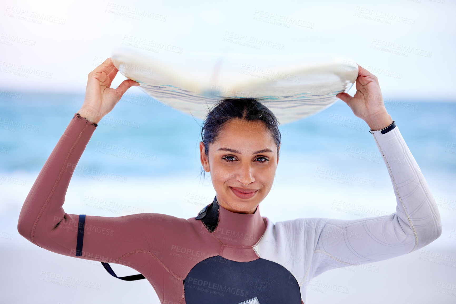 Buy stock photo Girl, portrait and surfboard on head at beach, workout and training for water sports competition. Female person, health and travel to ocean or sea for wave, fitness and athlete for exercise in nature