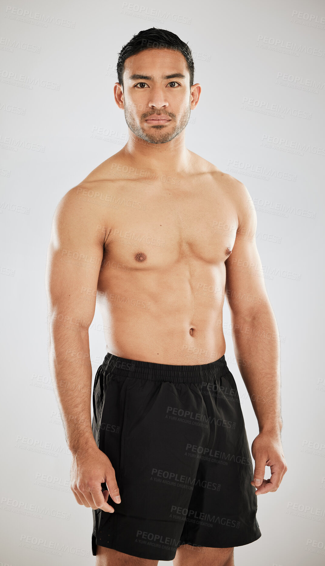 Buy stock photo Studio shot of a handsome young man showing off his muscular body while posing against a grey background