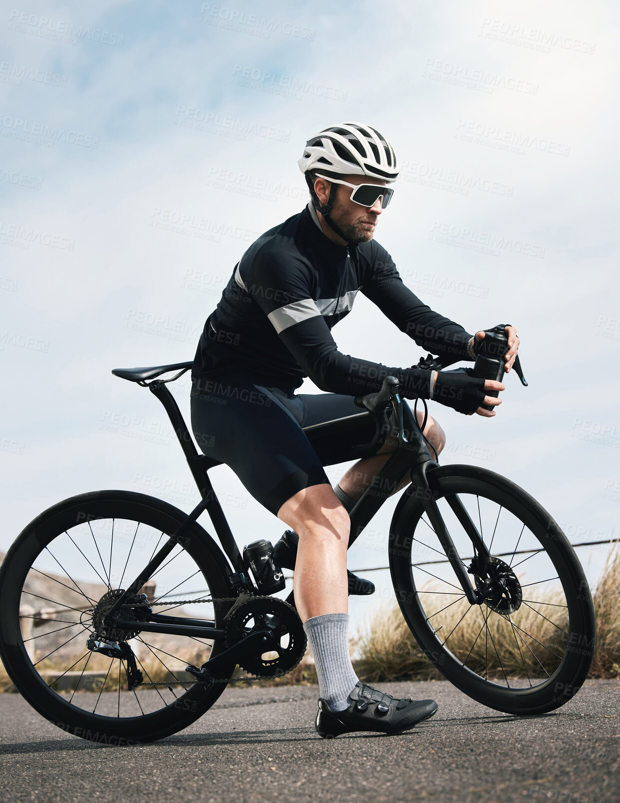 Buy stock photo Full length shot of a handsome mature man taking a water break while cycling outdoors