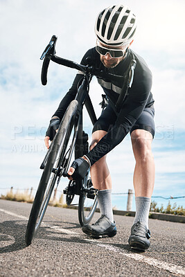 Buy stock photo Full length shot of a handsome mature man checking his tyre while cycling outdoors