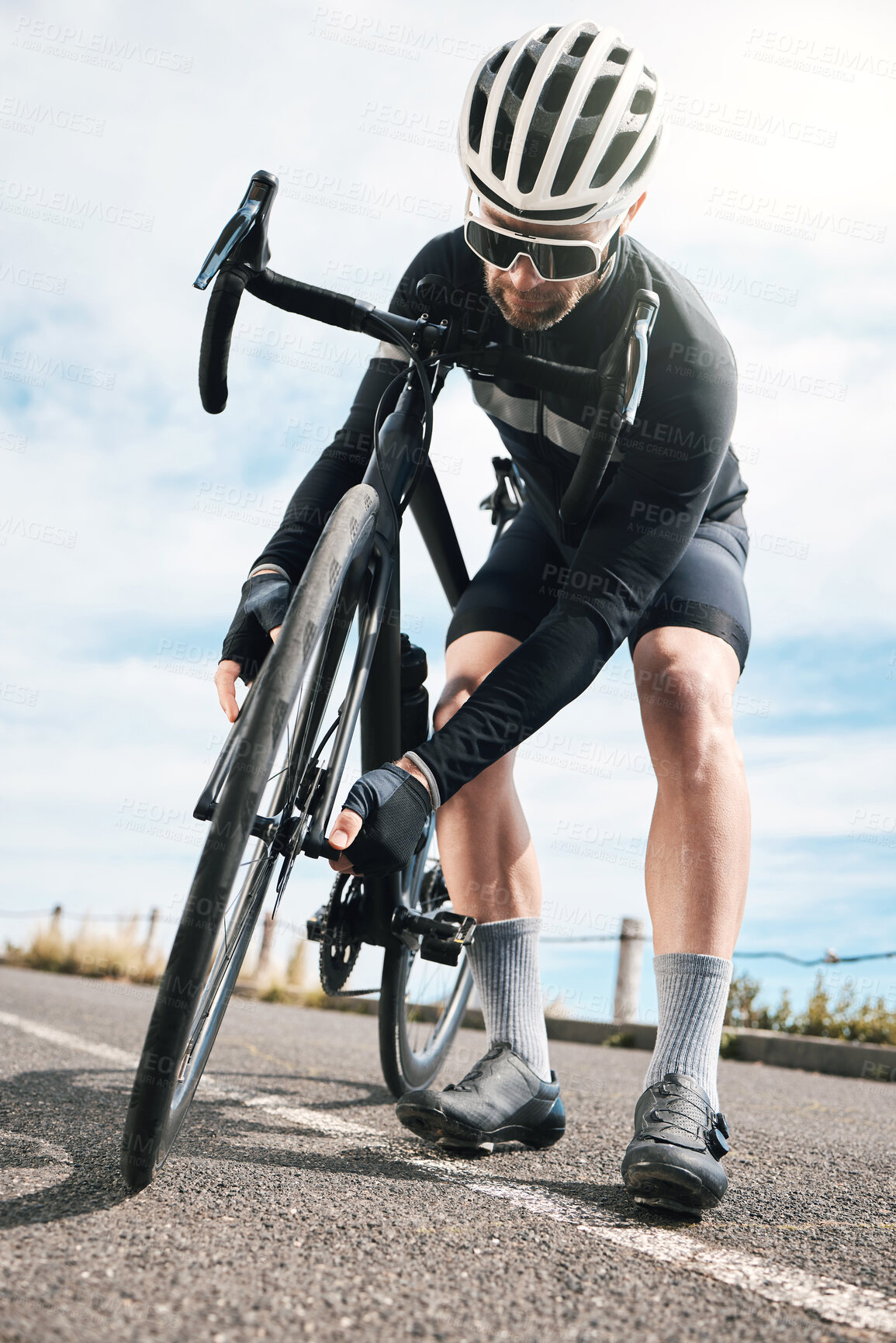 Buy stock photo Full length shot of a handsome mature man checking his tyre while cycling outdoors