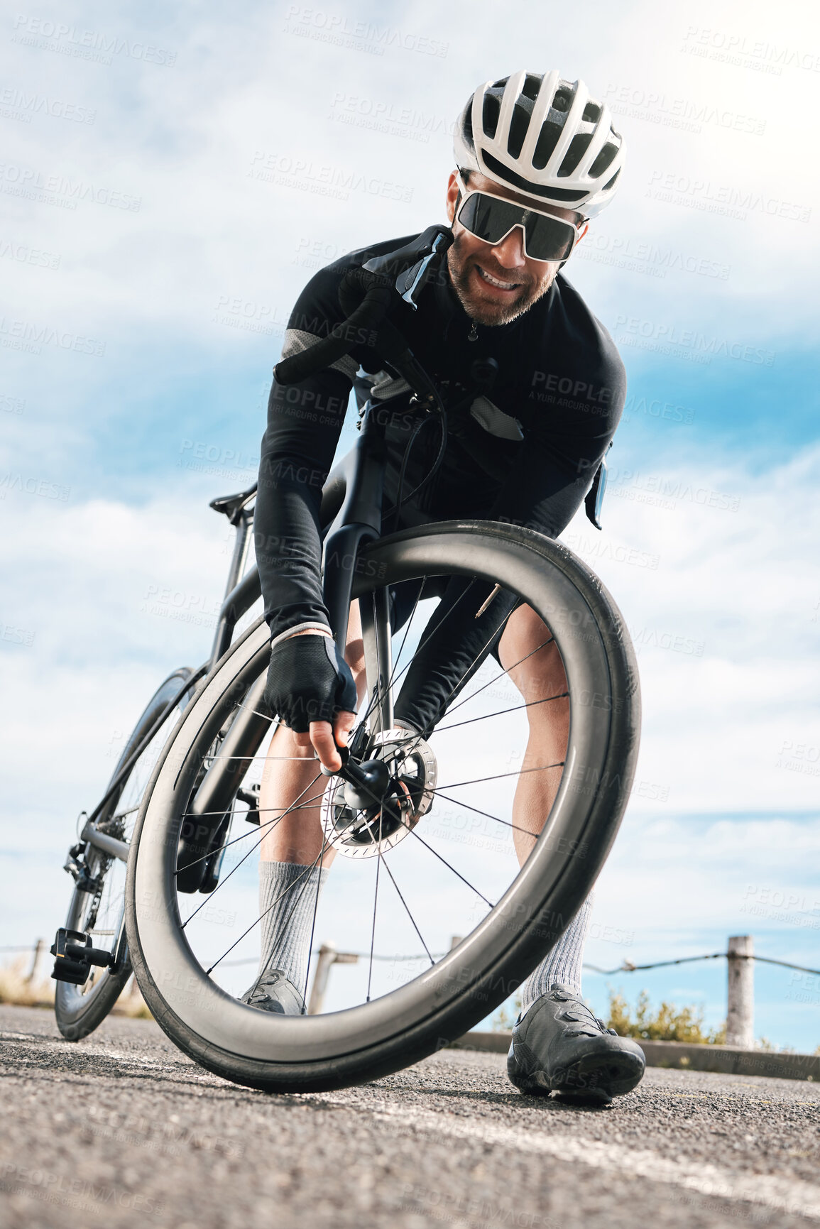 Buy stock photo Full length shot of a handsome mature man checking his tyre while cycling outdoors