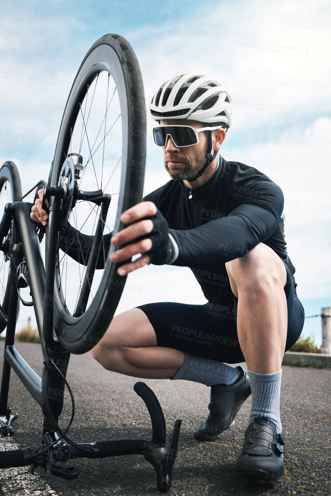 Buy stock photo Full length shot of a handsome mature man checking his tyre while cycling outdoors