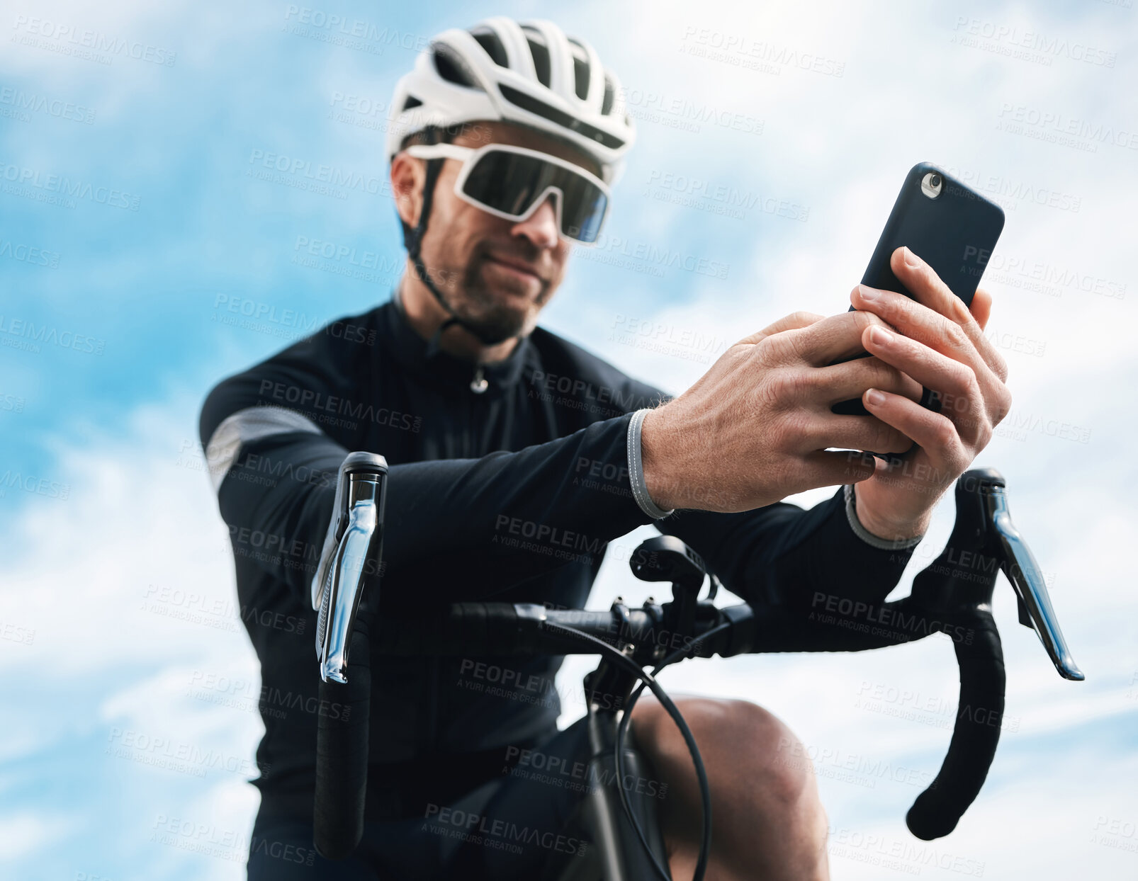 Buy stock photo Cropped shot of a handsome mature man sending a text while cycling outdoors