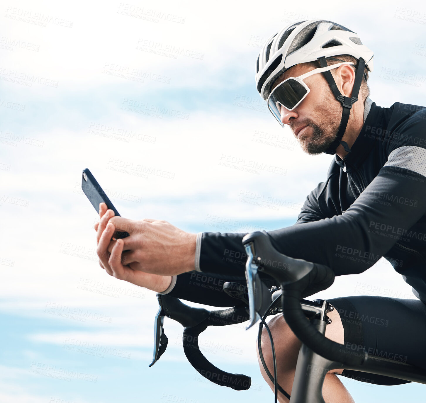 Buy stock photo Cropped shot of a handsome mature man sending a text while cycling outdoors