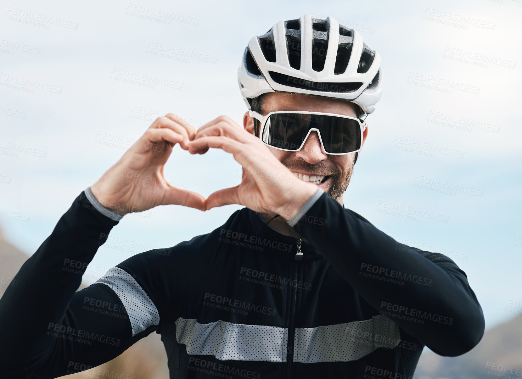 Buy stock photo Cropped shot of a handsome mature man making a heart shape with his hands while cycling outdoors