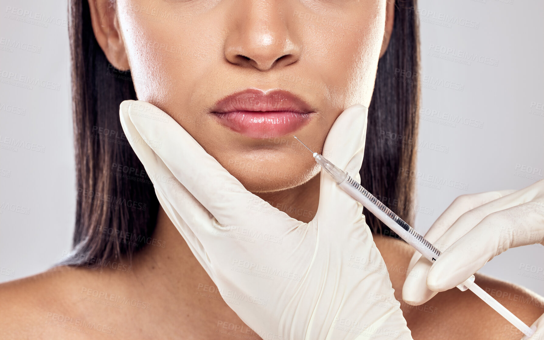 Buy stock photo Shot of a woman having her lips injected with filler against a studio background