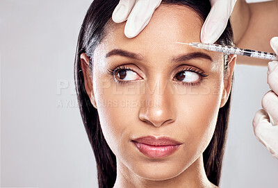 Buy stock photo Shot of a woman having her forehead injected with botox against a studio background