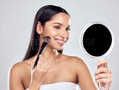 Buy stock photo Shot of a young woman applying cosmetic powder while looking into a mirror against a studio background