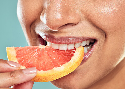 Buy stock photo Shot of a woman biting into a slice of grapefruit against a studio background