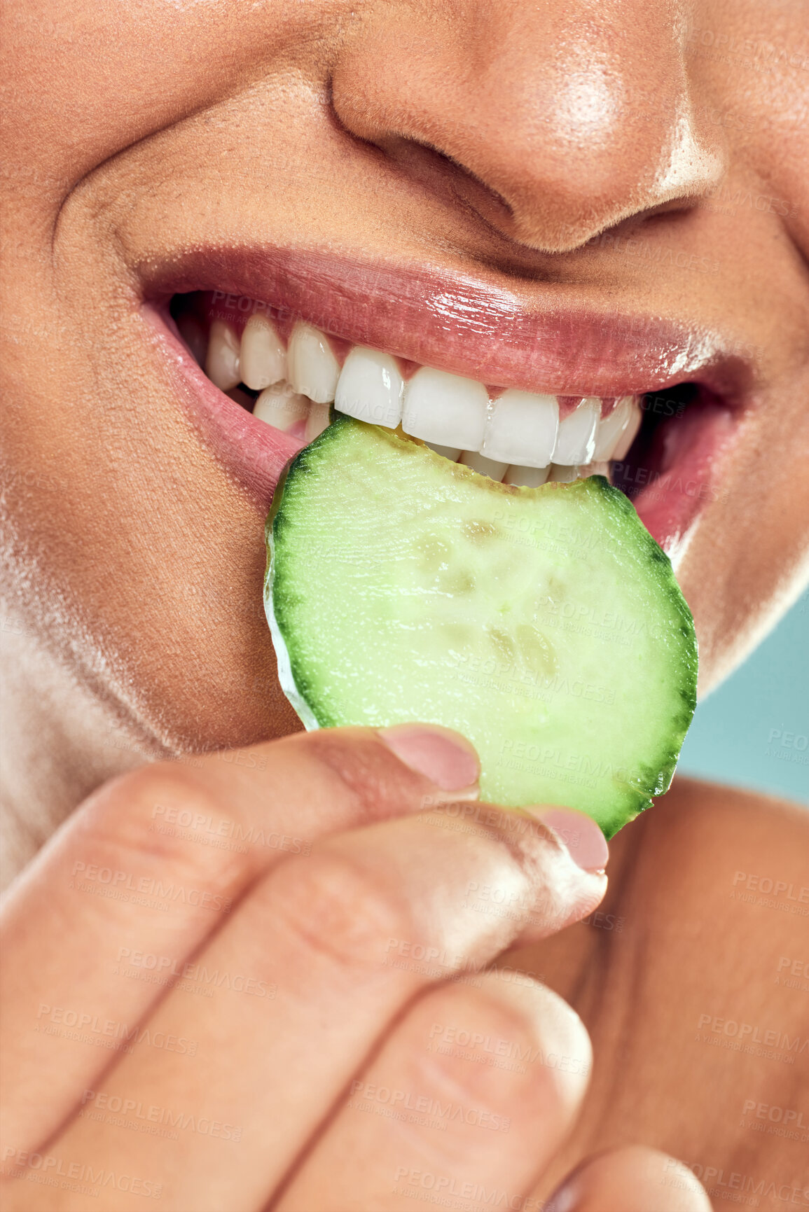 Buy stock photo Woman, cucumber and mouth for bite in studio, eco friendly and nutrition or vegetable. Female person, teeth and organic diet or vegan detox or wellness, snack and green benefits on blue background