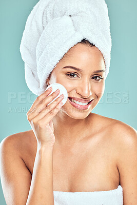 Buy stock photo Shot of a young woman applying product to her face using a cotton pad against a studio background