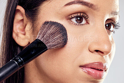 Buy stock photo Shot of a young woman applying face powder against a studio background