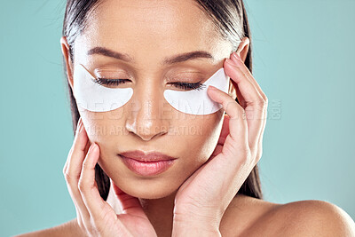 Buy stock photo Shot of a young woman using eye masks against a studio background