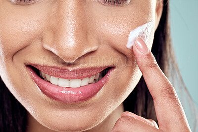 Buy stock photo Shot of a happy woman applying moisturiser against a studio background