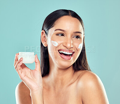 Buy stock photo Shot of a happy young woman applying moisturiser against a studio background