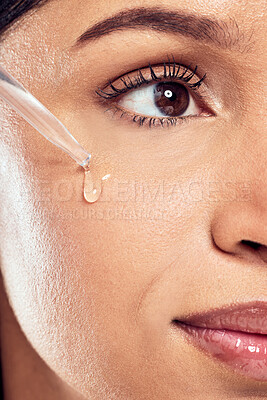 Buy stock photo Shot of a young woman applying facial serum against a studio background