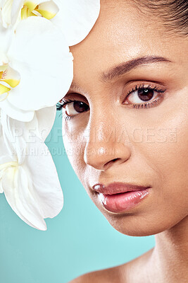 Buy stock photo Flowers, portrait and woman in studio with skincare, wellness and organic care on blue background. Natural beauty, female person and orchids for feminine hygiene or purity, growth and delicate skin