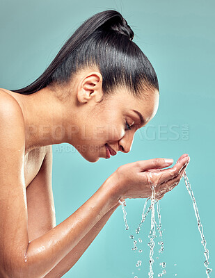 Buy stock photo Shot of a young woman washing her face and splashing water against a studio background