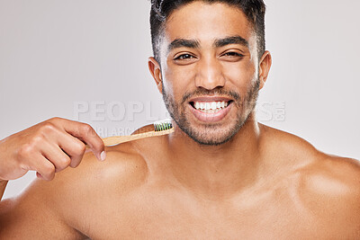 Buy stock photo Shot of a young man brushing his teeth against a grey background
