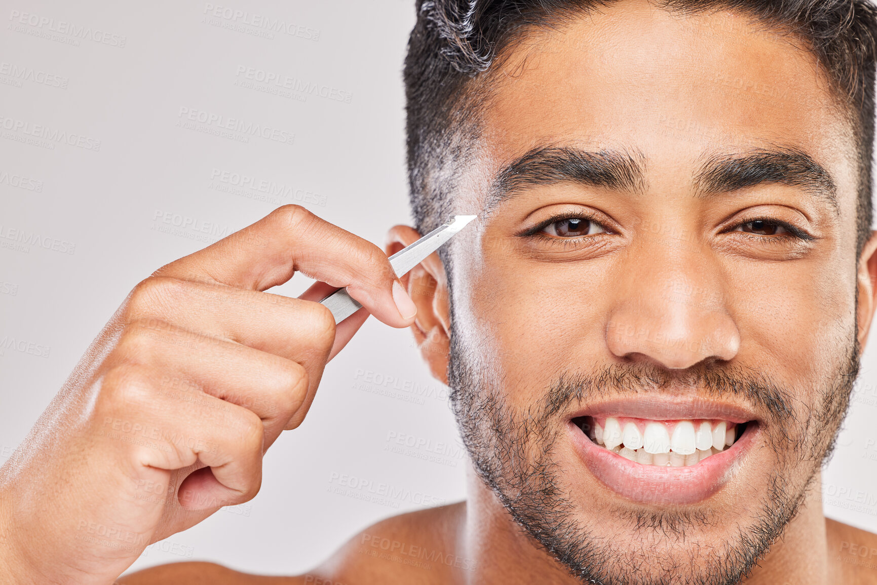 Buy stock photo Shot of a young man plucking his eyebrows against a grey background