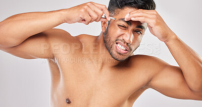 Buy stock photo Shot of a young man plucking his eyebrows against a grey background
