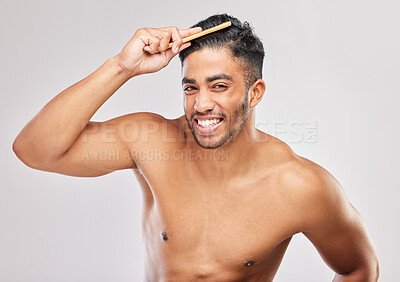 Buy stock photo Shot of a young man brushing his hair against a grey background