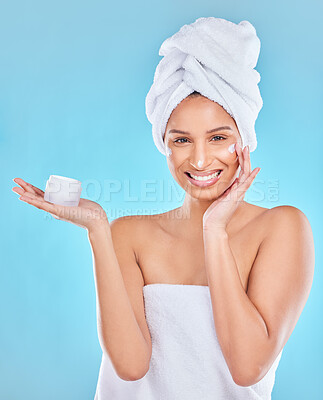Buy stock photo Studio portrait of an attractive young woman applying face moisturizer against a blue background