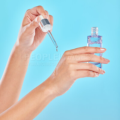 Buy stock photo Studio shot of an unrecognizable woman applyng antiaging serum to her hands against a blue background
