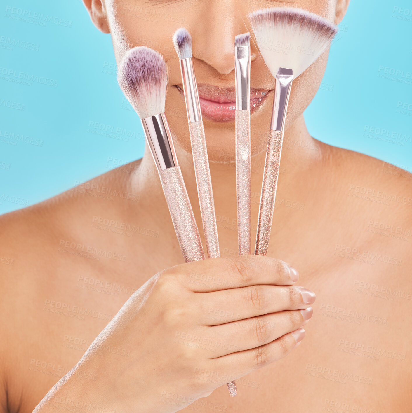 Buy stock photo Creative, makeup and girl with brushes in hand for application of cosmetics in blue background. Studio, beauty and artist with tools to apply foundation, powder or product in skincare with smile