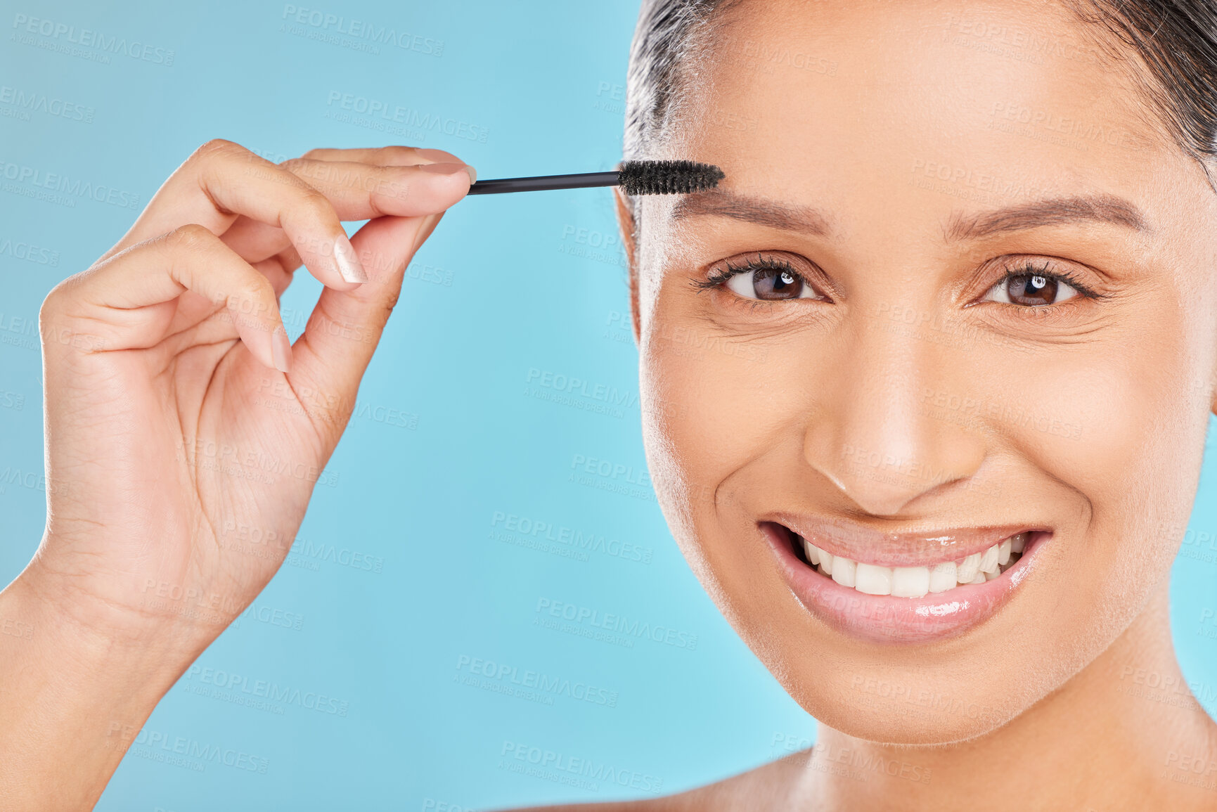 Buy stock photo Portrait, eyebrows and happy woman with mascara makeup for beauty, cosmetics product or wellness in studio. Indian girl, face or model with brush, skincare or application results on blue background