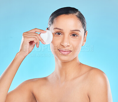 Buy stock photo Studio portrait of an attractive young woman exfoliating her face against a blue background