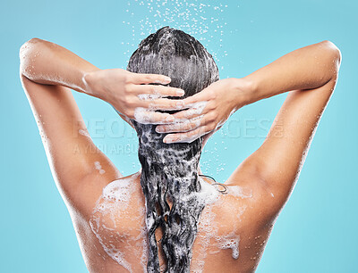 Buy stock photo Back, shower and woman with skincare, foam and hair care on blue studio background. Rear view, person or model with water drops, shampoo or cleaning with liquid, grooming routine or wet with wellness