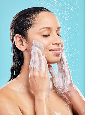 Buy stock photo Shot of a young woman washing her face against a blue background